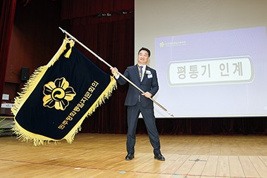 신임 김성주 회장이 평통기를 인계받고 깃발을 흔들어 보이고 있다.