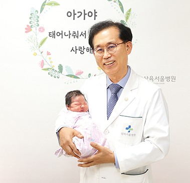 양거승 병원장이 12일 태어난 일곱째 신생아를 안고 있는 모습.